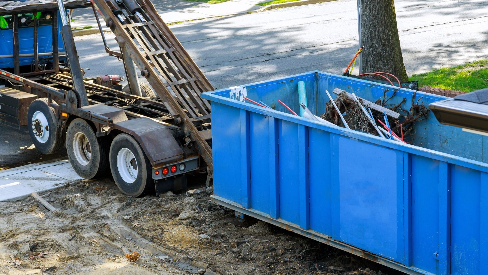 Blue dumpster and truck on construction site with debris and dirt