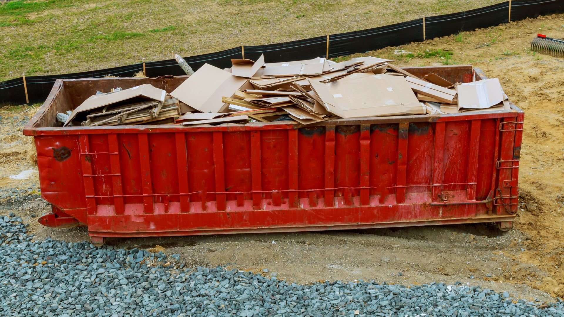 Red dumpster filled with cardboard and wood debris at construction site