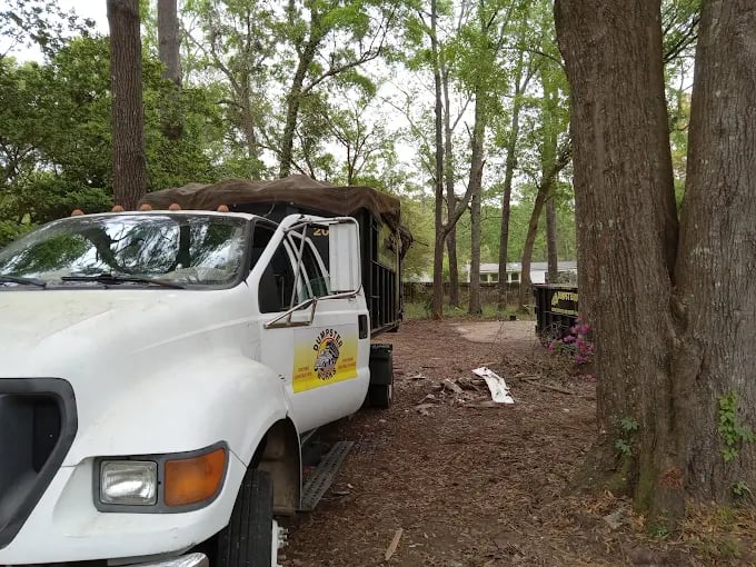 White work truck parked on forest trail with trees in background
