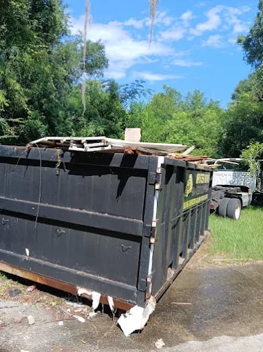 Large black dumpster filled with construction debris, parked outdoors